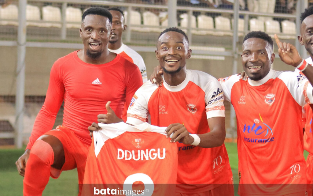 Derrick Ddungu holds up his Express FC shirt while celebrating with teammates after scoring against KCCA FC.