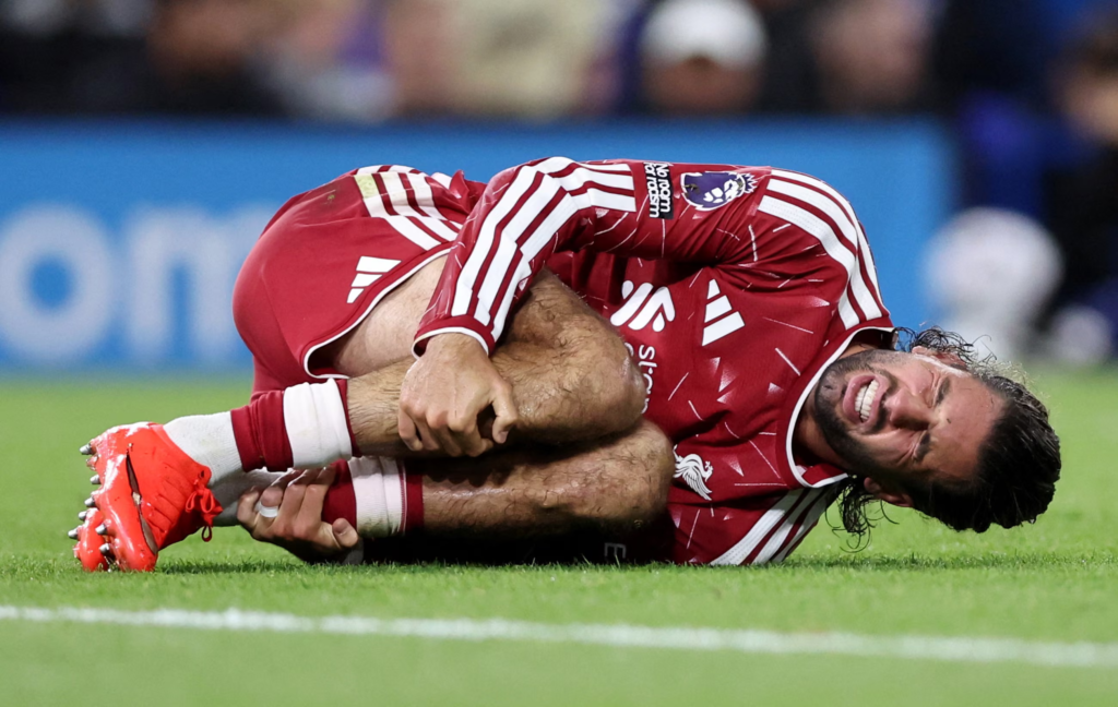 Liverpool's Dominik Szoboszlai grimaces in pain, curled up on the grass clutching his leg, following a tackle during the match against Ipswich Town.
