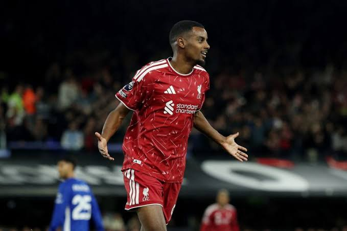 Liverpool's Alexander Isak celebrates with arms outstretched after scoring, with an Ipswich Town defender in the background.