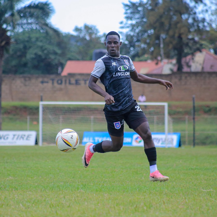 SC Villa player Ssemakula Aslam in a black and grey Linglong-sponsored kit runs after the ball near the goal post on the pitch.