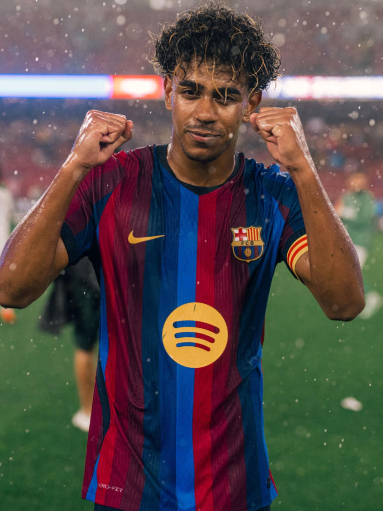Lamine Yamal raises both fists in celebration while wearing Barcelona’s home jersey during the rain-soaked match against Racing Santander.