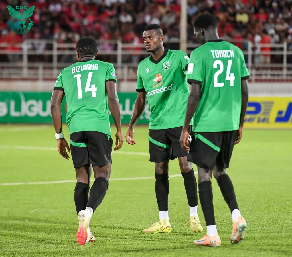 Rogers Torach Ochaki in CS Constantine’s green number 24 jersey standing alongside two teammates on the pitch.