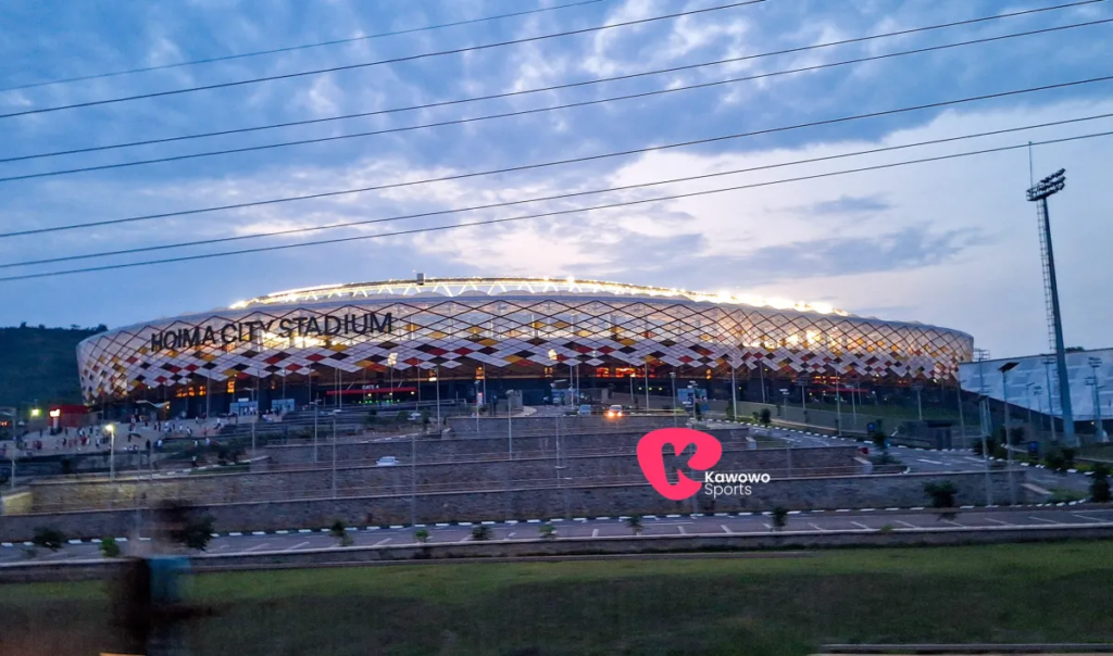 Illuminated exterior of Hoima City Stadium in western Uganda under a cloudy evening sky.