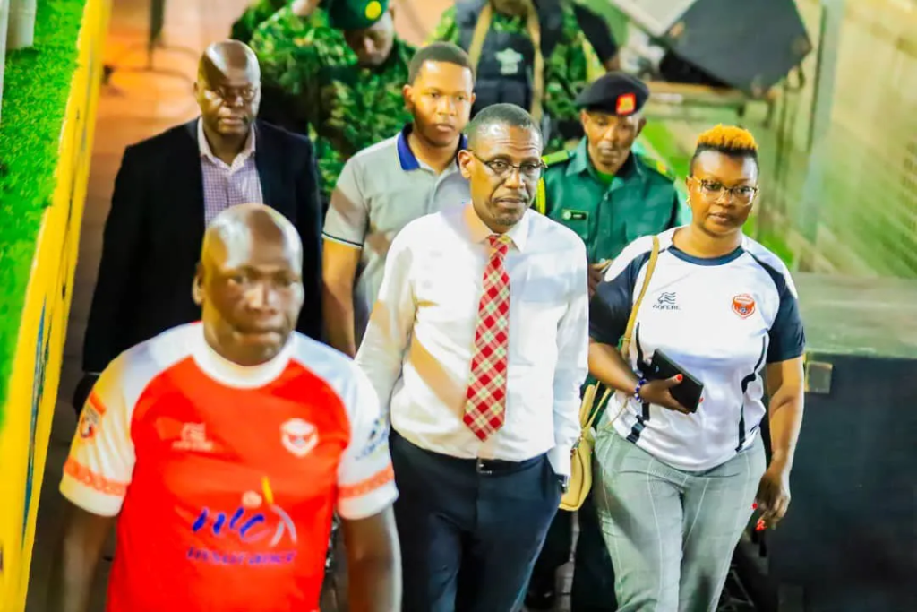 Kiryowa Kiwanuka walks through Hamz Stadium alongside Express FC officials and security personnel.