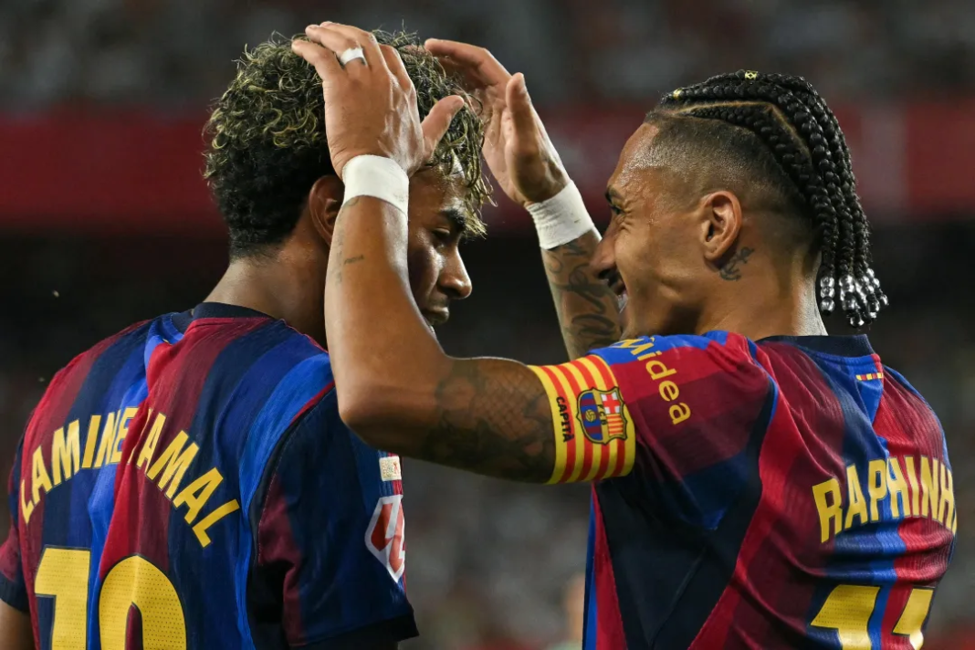 Barcelona forward Raphinha celebrating with teammate Lamine Yamal after scoring his team's second goal against Sevilla.