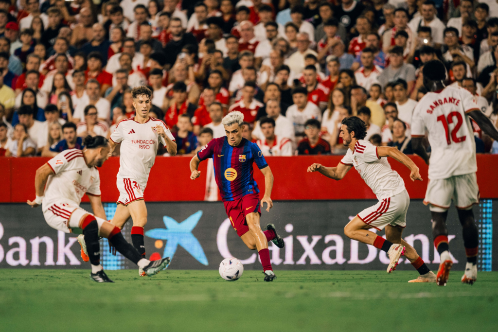 Pedri carries the ball between Sevilla defenders during the match.