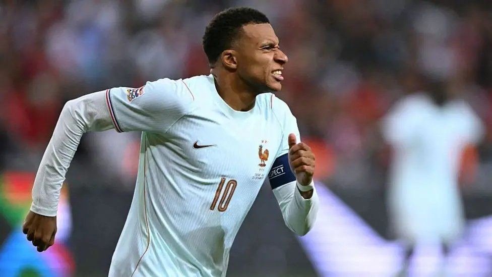 France forward Kylian Mbappé grimacing in pain as he celebrates scoring a goal.