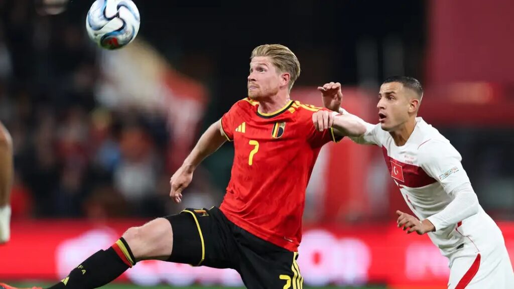 Belgium captain Kevin De Bruyne challenging for the ball against a Türkiye player.