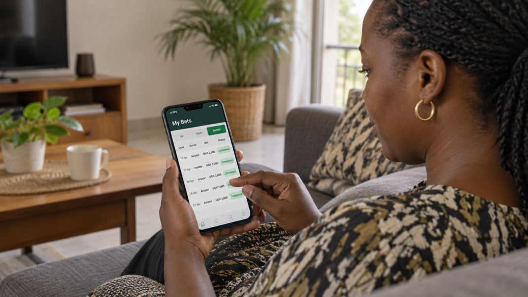 Ugandan woman checking My Bets history on smartphone.