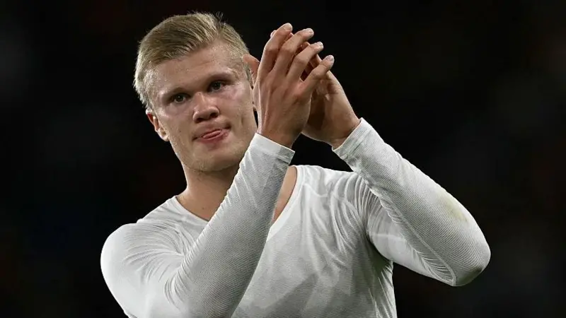 Norway forward Erling Haaland applauding fans in a white kit after a match.