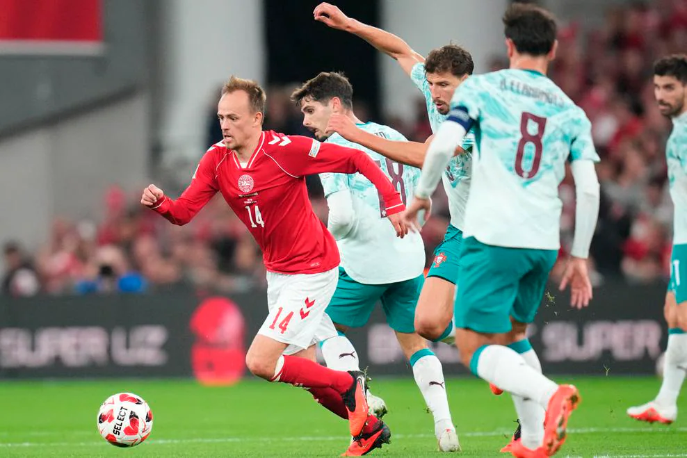 Denmark forward Mikkel Damsgaard, wearing No. 14, running with the ball past Portugal defenders, including No. 8, at Parken, Copenhagen.