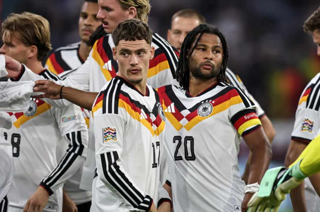 Germany players, including No. 17 and No. 20, standing together on the pitch during their match.