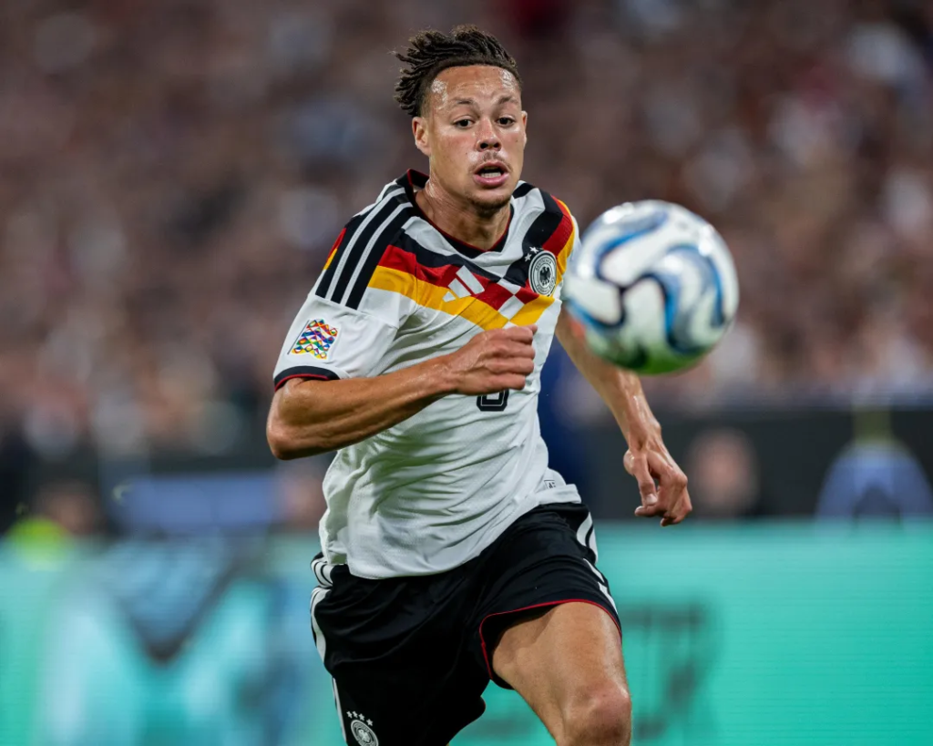 Germany player in a white kit running after the ball during a match