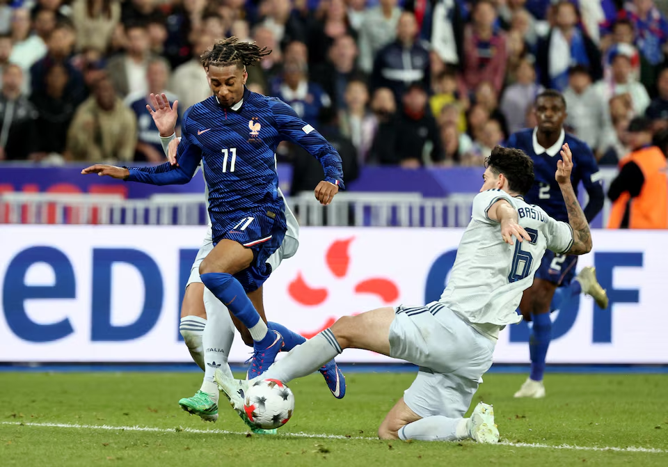 France's Michael Olise challenging Italy's Alessandro Bastoni for the ball during their match.