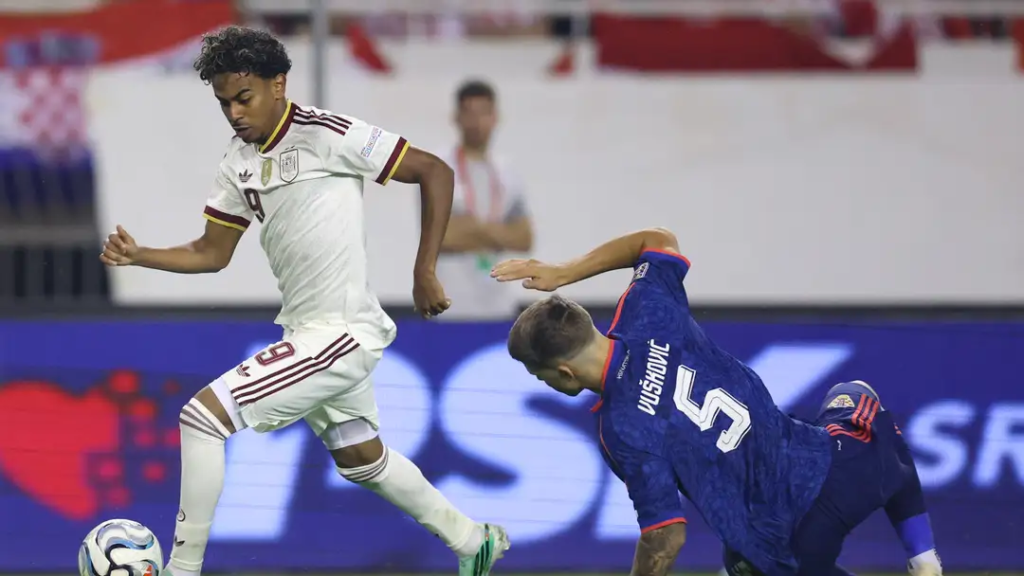 Spain forward Lamine Yamal, in white, dribbling past Croatia's Vušković, wearing No. 5.