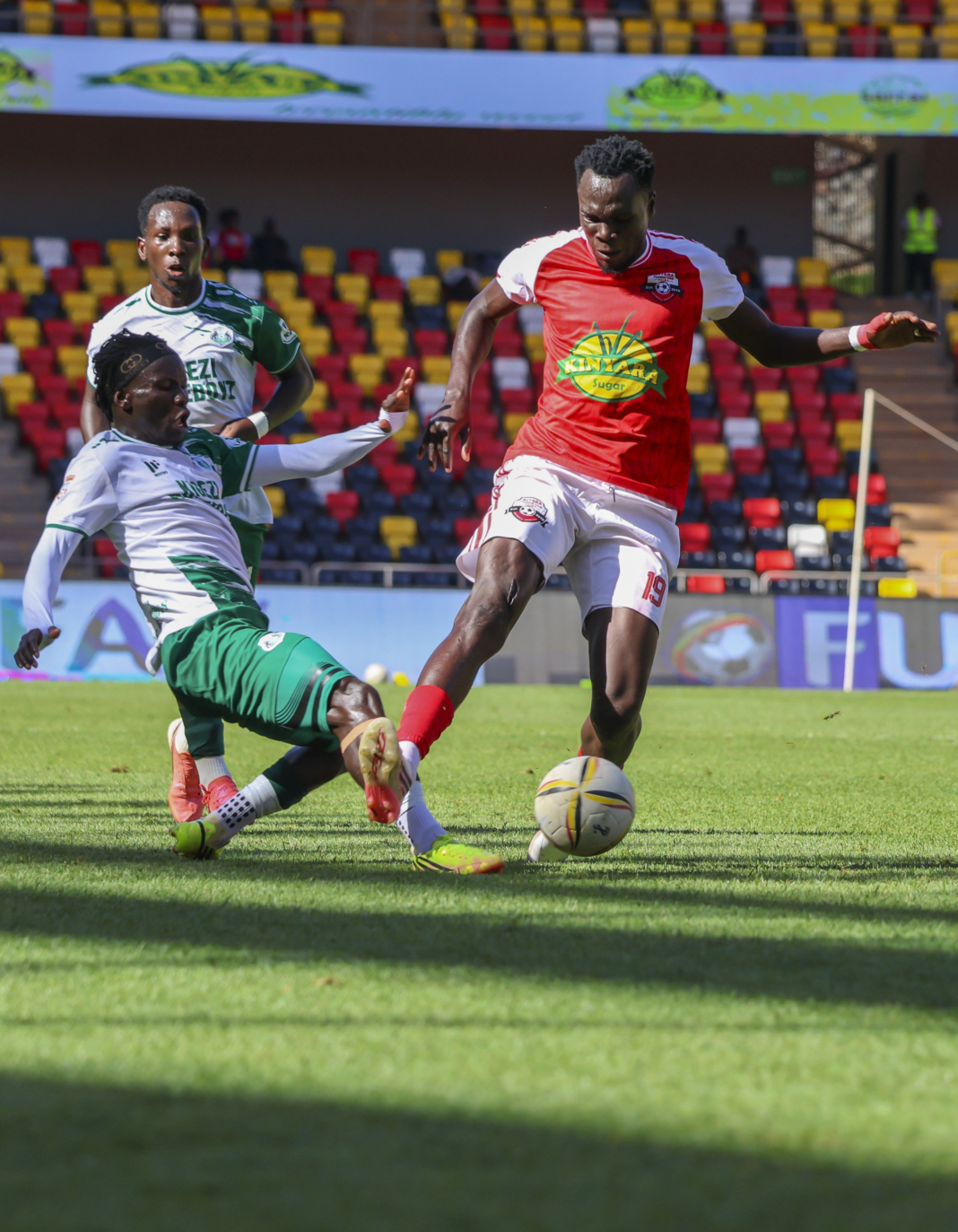 Kigezi HomeBoyz player challenges Kitara FC defender during a football match.